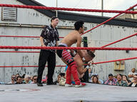 building crew_cut crowd fight pose:bent_forward pose:kneeling pose:standing shirtless short_hair sport squared_circle subject:human type:photograph wrestler wrestling // 2667x2000 // 734KB
